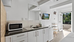 Eine moderne Küche mit Mikrowelle, Spüle und Schränken. Ein großes Fenster bietet Blick ins Freie.