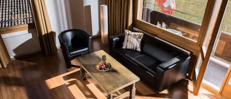 Una sala de estar moderna con una mesa de centro de madera, un sofá de cuero negro y vista a una bandera en el exterior.