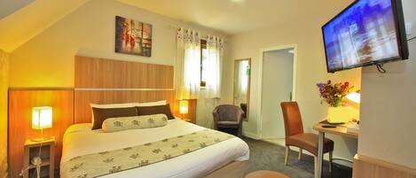 Habitación de hotel con cama, escritorio, silla, televisión y un cuadro en la pared.