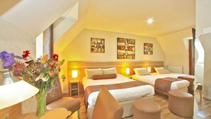 A hotel room with two beds, a desk, a chair, and a vase of flowers. - Hostellerie du Causse (Gramat)