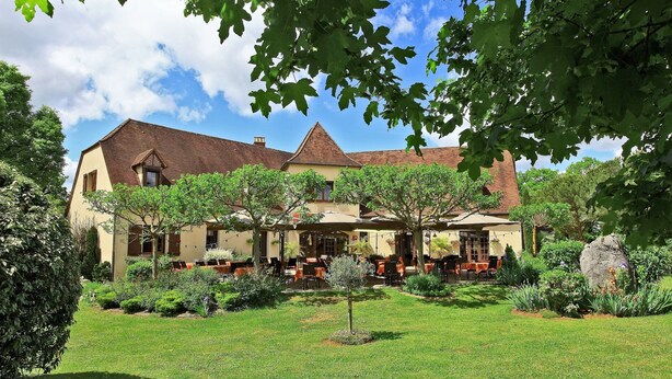 A large building with a garden in front, featuring outdoor seating and a variety of plants. - Hostellerie du Causse (Gramat)