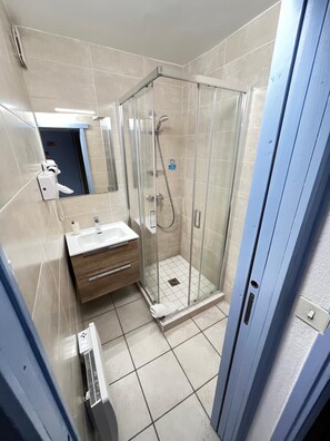 A bathroom with a glass-enclosed shower, a sink, and a mirror.