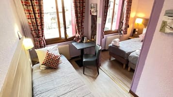 A small, compact room with two beds, a desk, and a mirror.