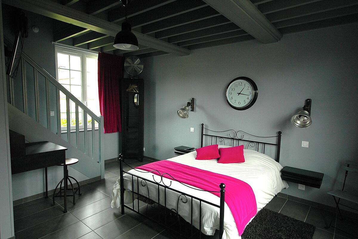 A bedroom with a bed, a desk, a chair, a clock, and a window.