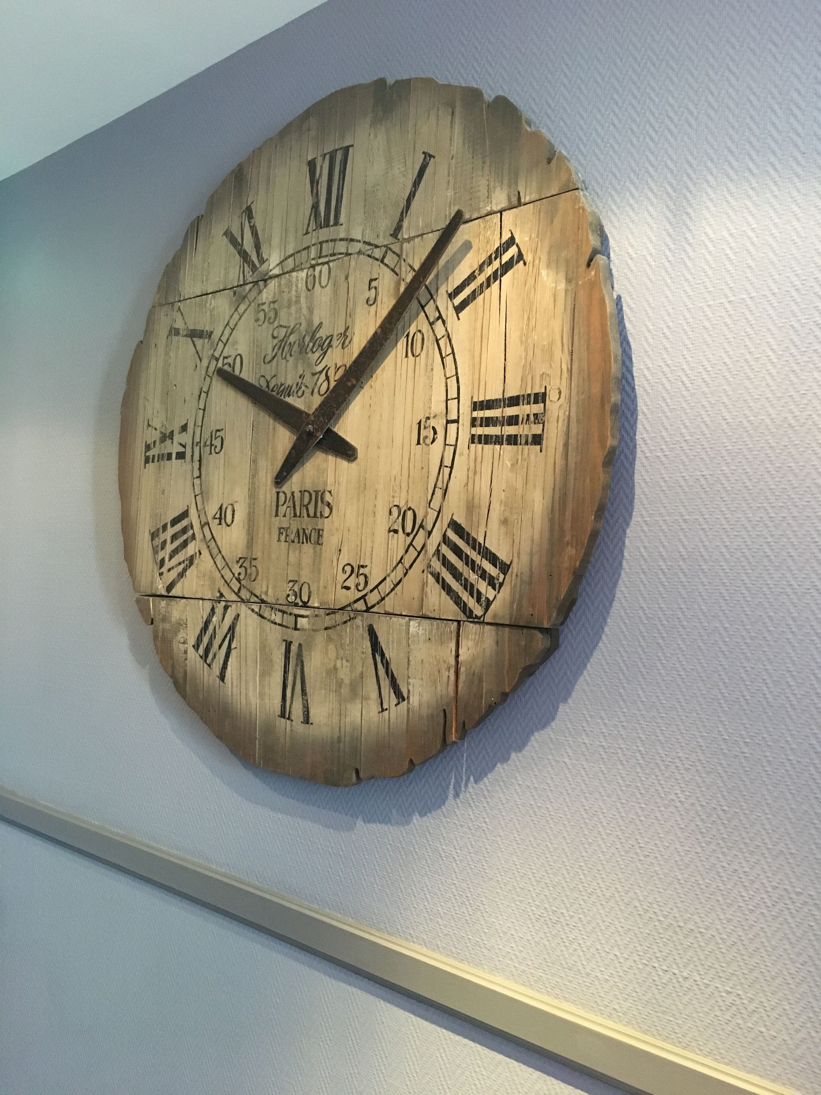 Une horloge en bois avec des chiffres romains et les mots « PARIS » et « FRANCE » inscrits dessus.