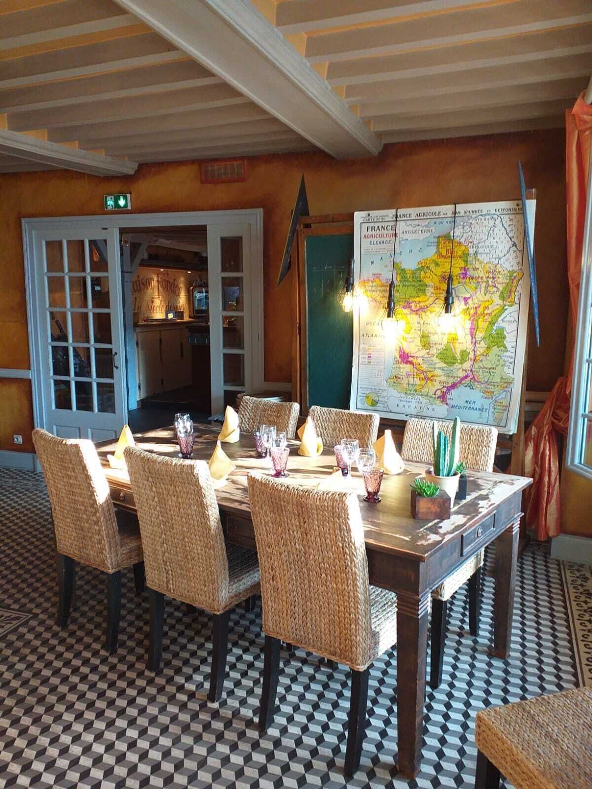 A dining area with a large map on the wall, wicker chairs, and a checkered floor.