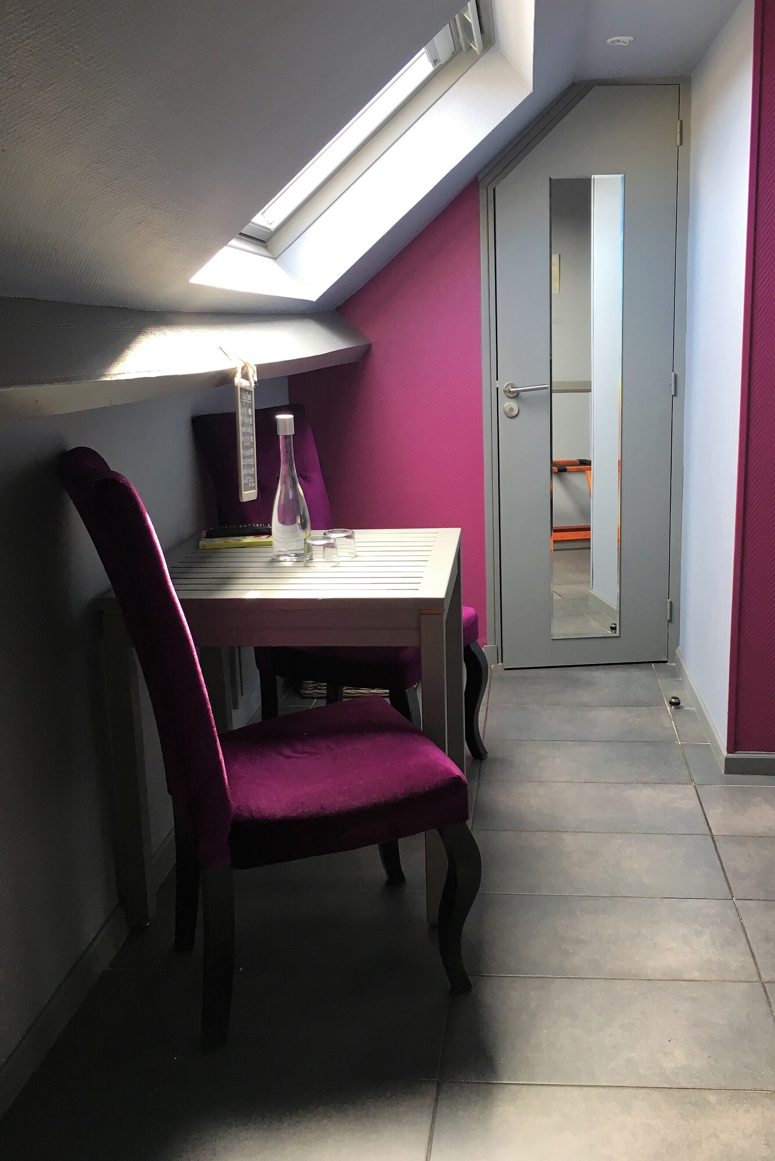 A small room with a table, a chair, a bottle, and a mirror.