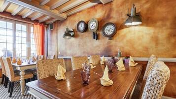 A dining area with a wooden table set for a meal, surrounded by wicker chairs.