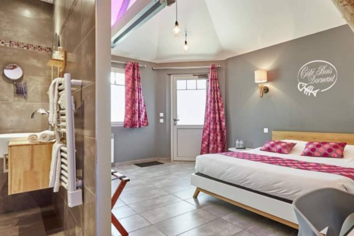 A modern hotel room with a large bed, a bathroom with a bathtub, and a shower area.