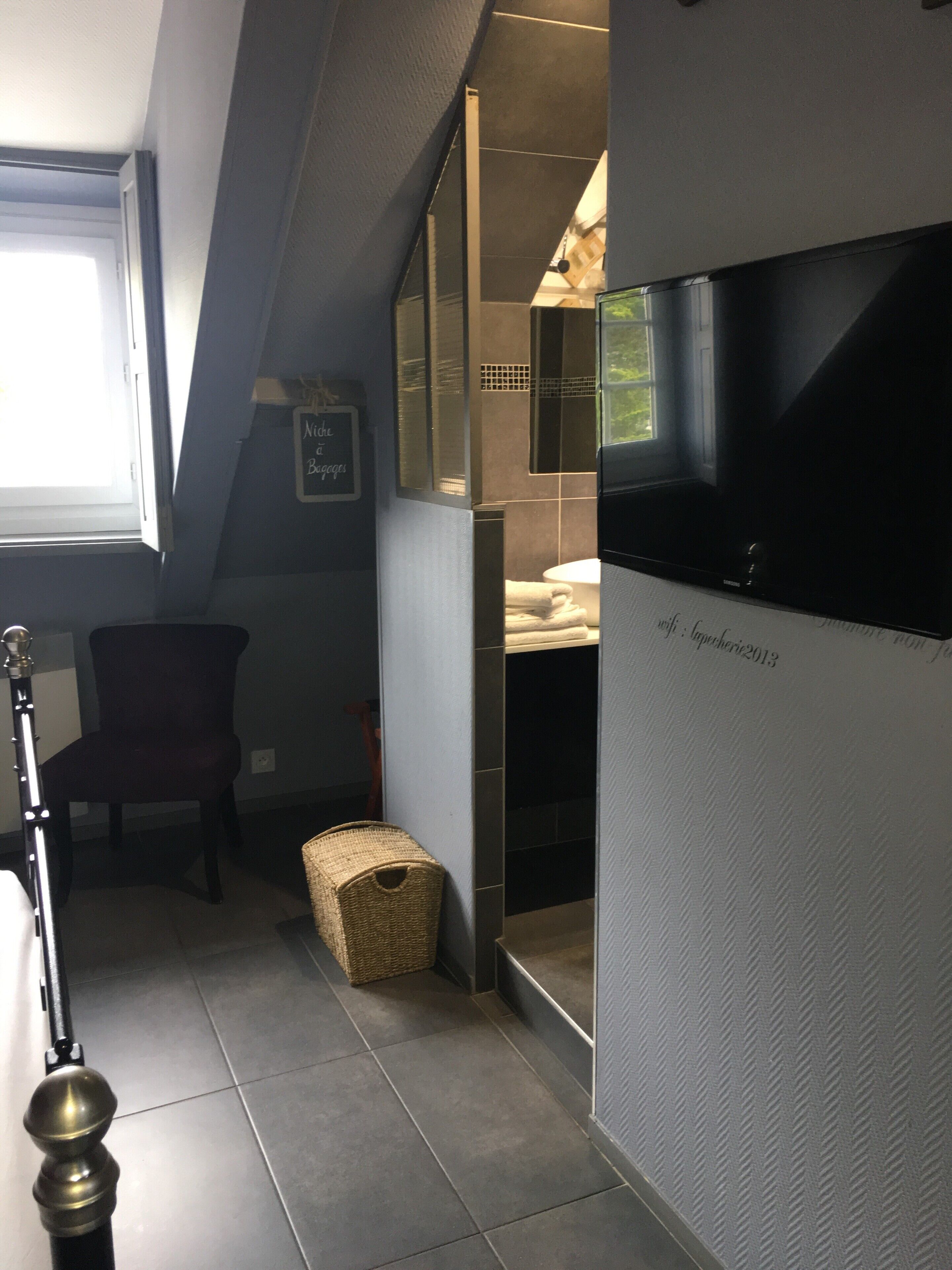 Ett badrum med badkar, en stol, en korg av rotting och en handduksställning.