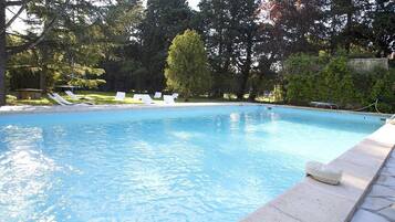 Una piscina al aire libre de temporada, sillones reclinables de piscina