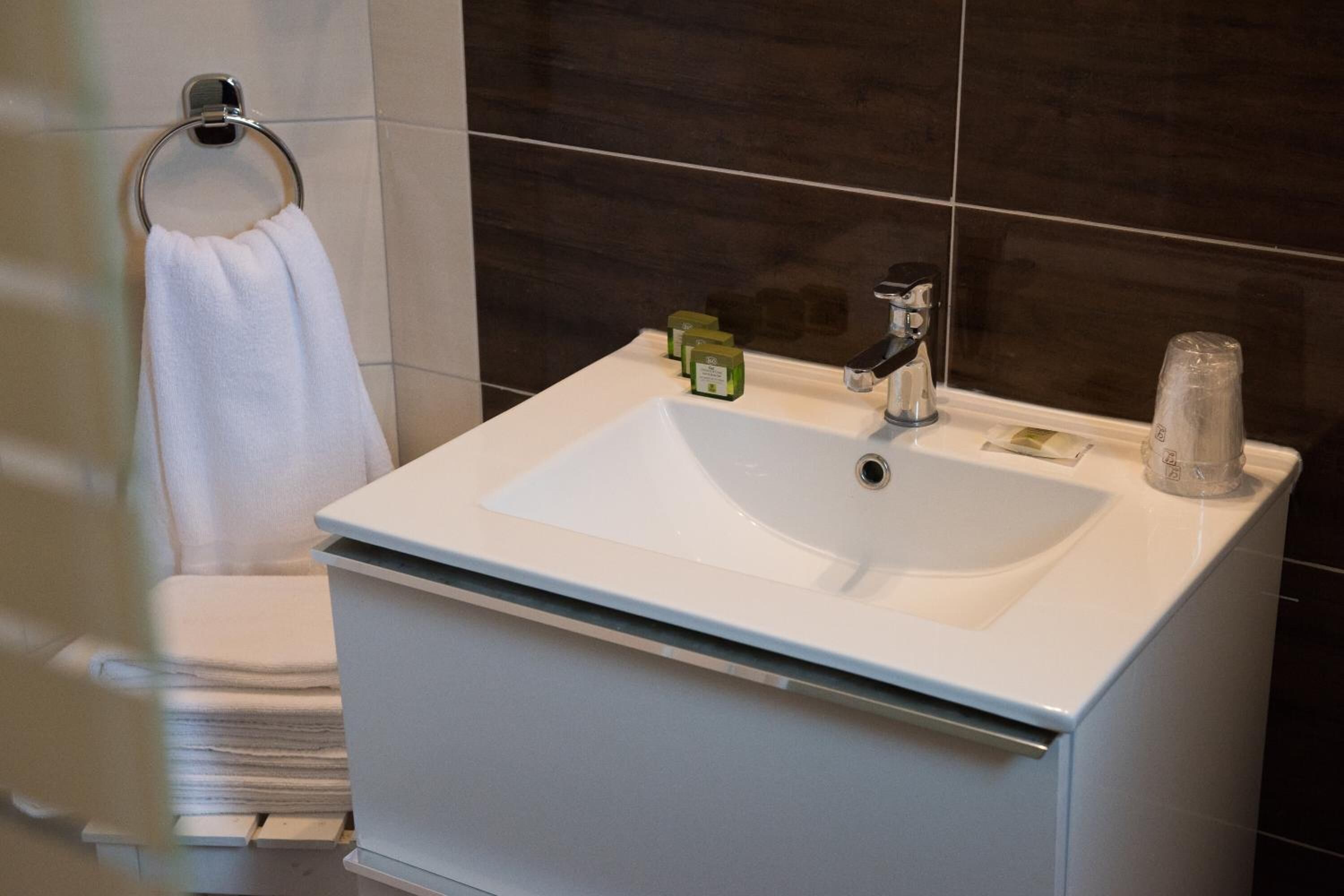 Un baño con un lavamanos blanco, un perchero para toallas y un espejo.