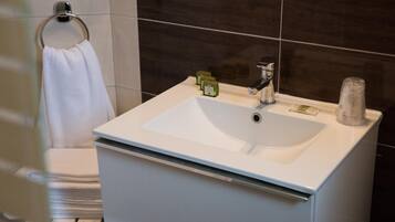 Un baño con un lavamanos blanco, un perchero para toallas y un espejo.
