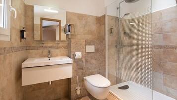 Un baño con lavamanos, inodoro y ducha.