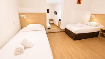 Une chambre d’hôtel avec deux lits simples, un plancher en bois, une petite table de chevet et un miroir.