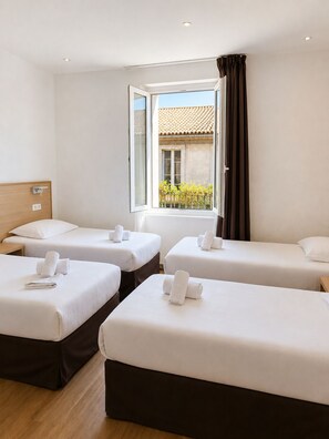 A hotel room with three beds arranged in a row, a window with curtains, and a view of the outside. - Hôtel Holzer II (Porto-Vecchio)
