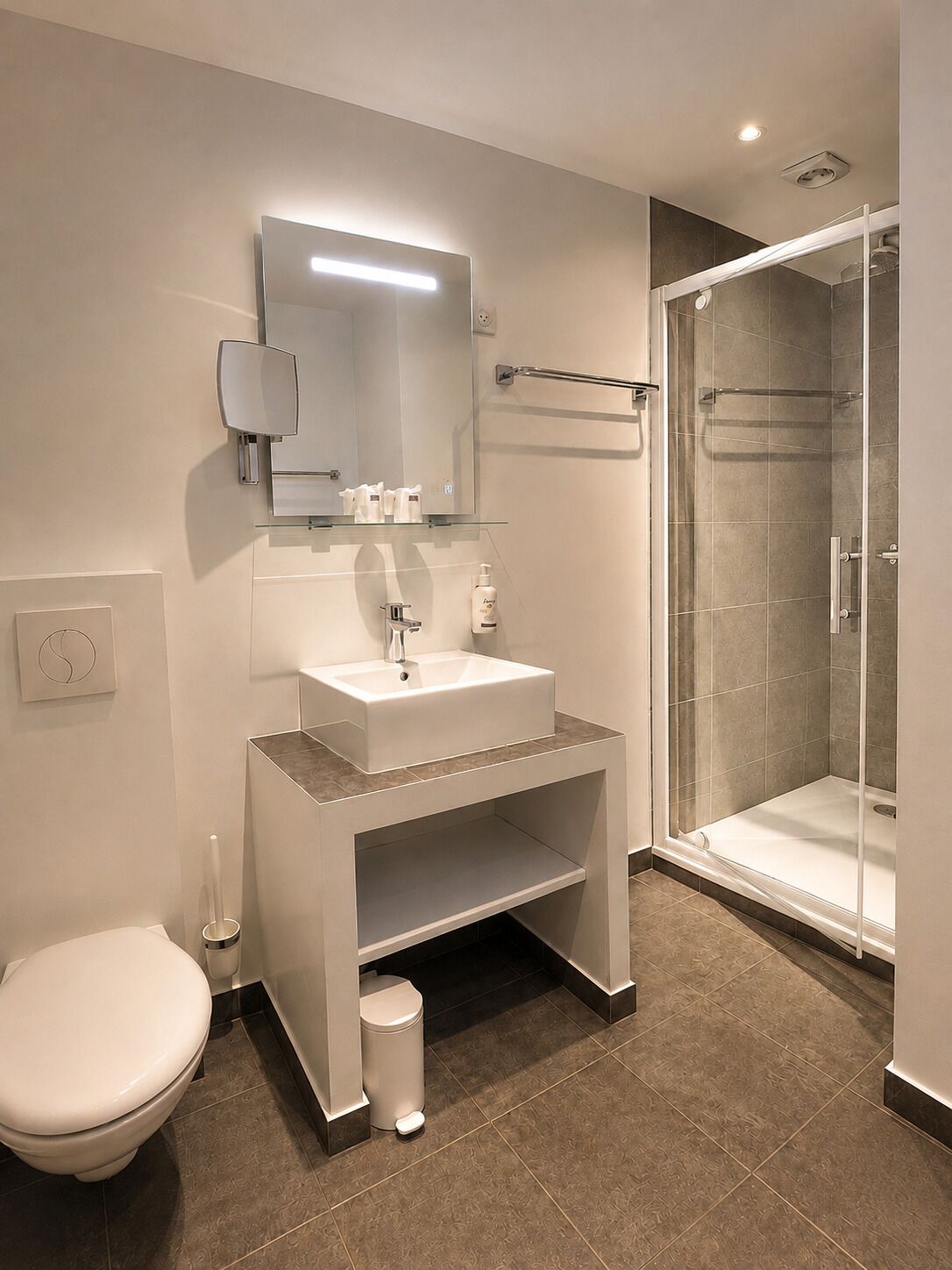 A modern bathroom with a white sink, mirror, and a glass shower enclosure.