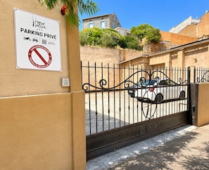 A gated entrance to a hotel with a sign indicating private parking. - Hôtel Holzer II (Porto-Vecchio)