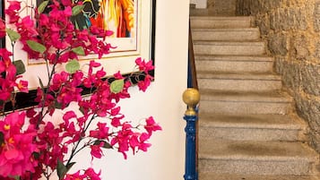 A staircase with stone walls and a framed painting of colorful figures.
