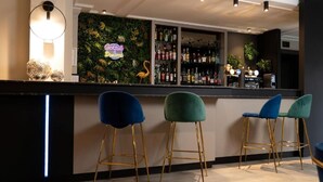 A bar area with a neon sign, a wall of plants, and a shelf of liquor bottles. - Les Tuileries (Fey)