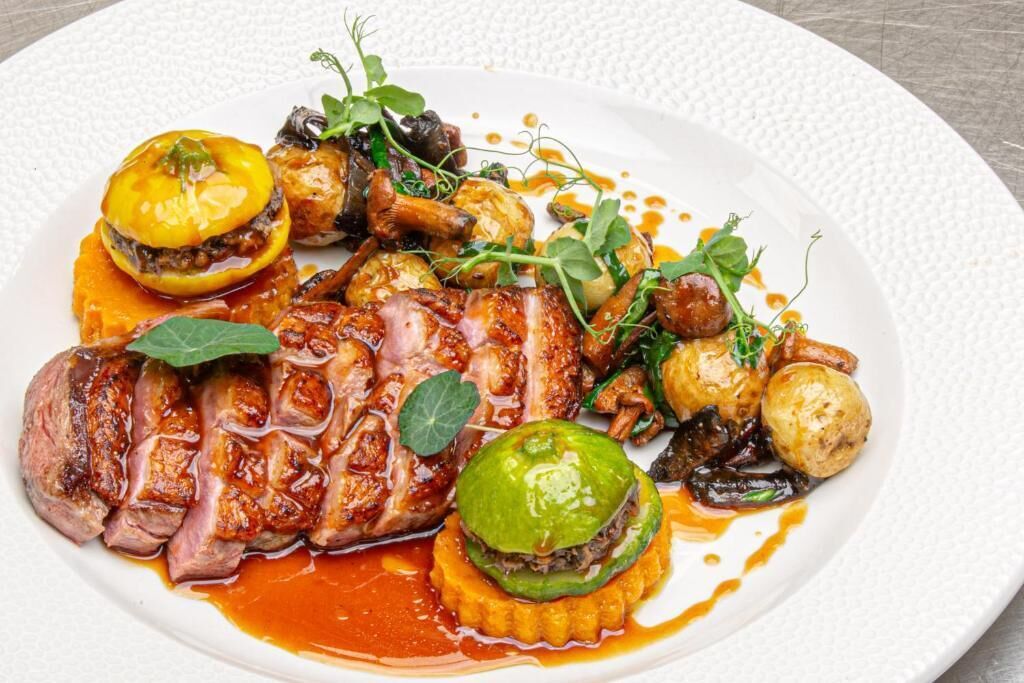 A plate of food with various dishes including meat, vegetables, and a sauce.