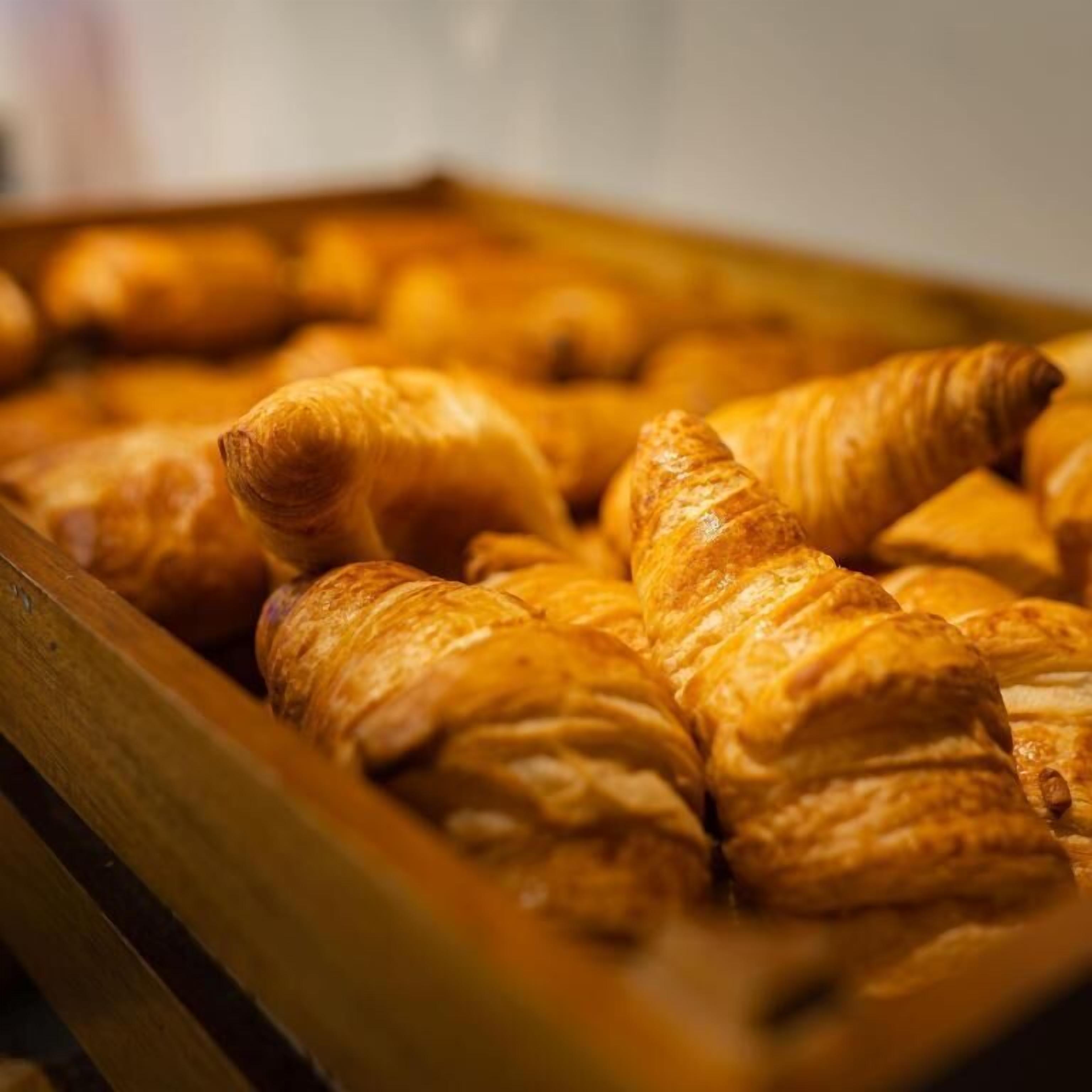 Ein Holztablett mit goldbraunen Croissants.