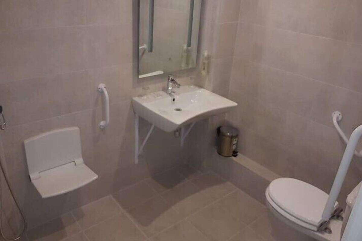 A bathroom with a white toilet, a sink, and a mirror.