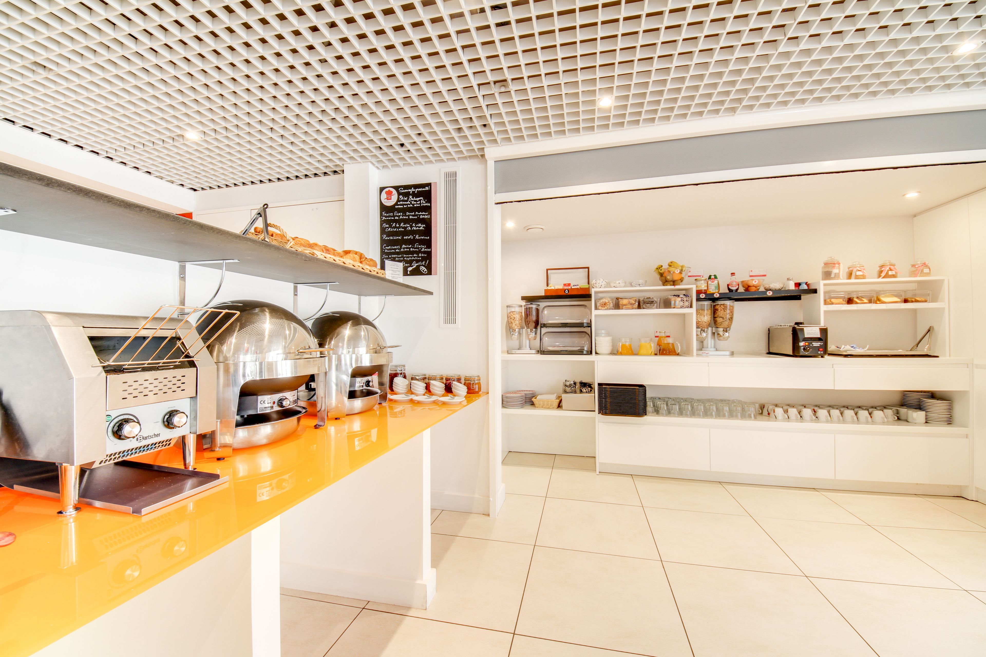 Una cocina moderna con electrodomésticos de acero inoxidable, una encimera naranja brillante y armarios blancos.