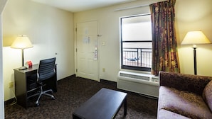 A hotel room with a desk, chair, couch, and two lamps. - OYO Hotel LSU (Port Allen)