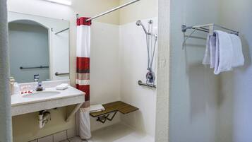 A bathroom with a sink, mirror, shower, and towel rack.