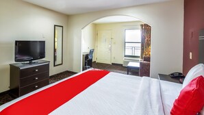 A hotel room with a bed, a TV, a desk, and a chair. - OYO Hotel LSU (Port Allen)