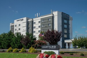 Um hotel Courtyard by Marriott com design moderno, com vários andares e uma bandeira.