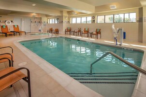 Piscina com cadeira de salva-vidas, espreguiçadeiras e guarda-sol.