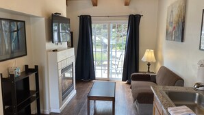 Una sala de estar acogedora con chimenea, televisor, sofá, mesa y una zona de cocina con fregadero y encimera.