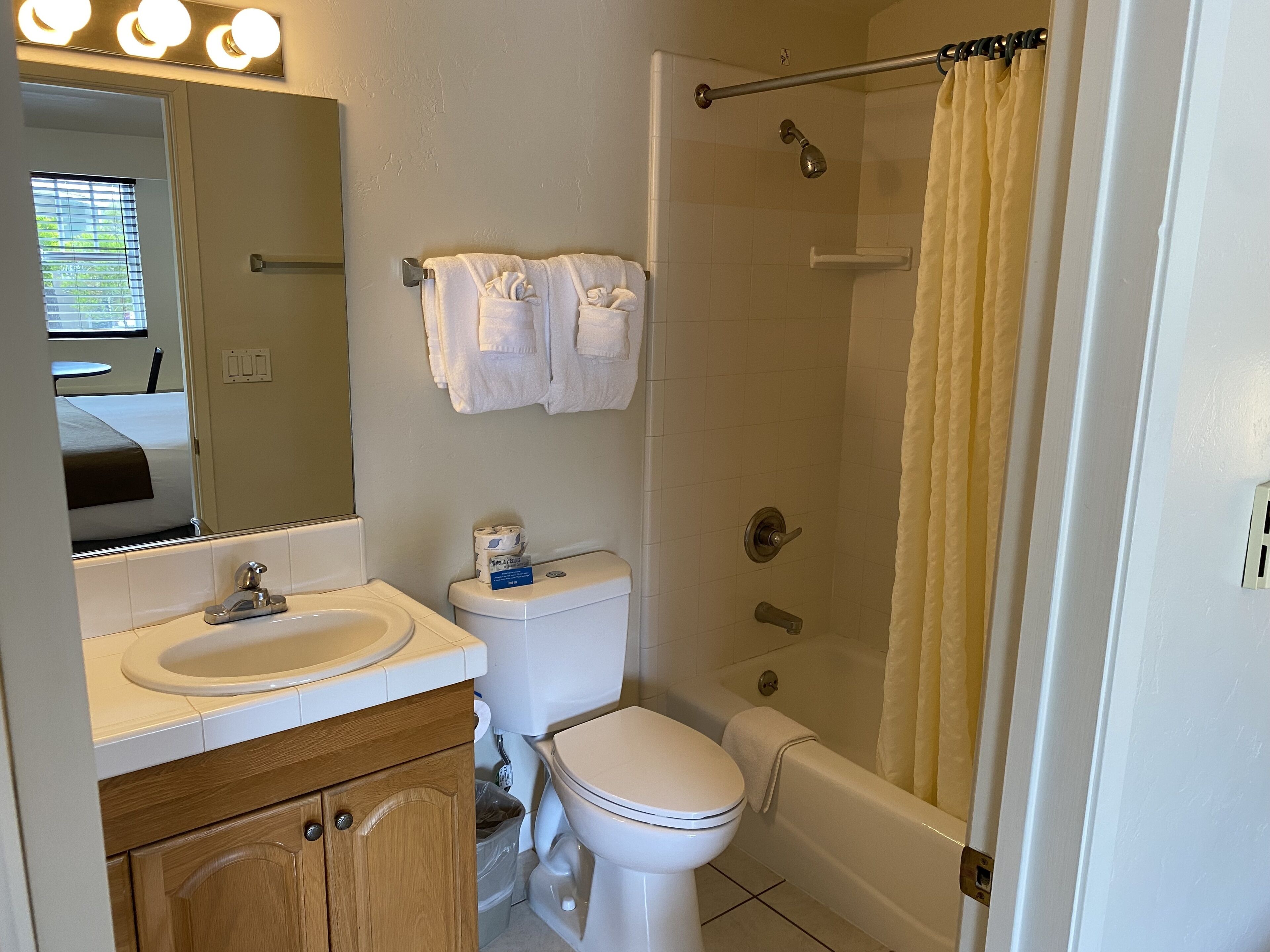 A bathroom with a sink, toilet, and bathtub. There are towels hanging on the wall and a shower curtain.