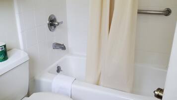 A bathroom with a toilet, a bathtub, and a shower curtain.