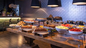 Un bufé con diferentes opciones de comida, un muro de ladrillo y lámparas colgantes.