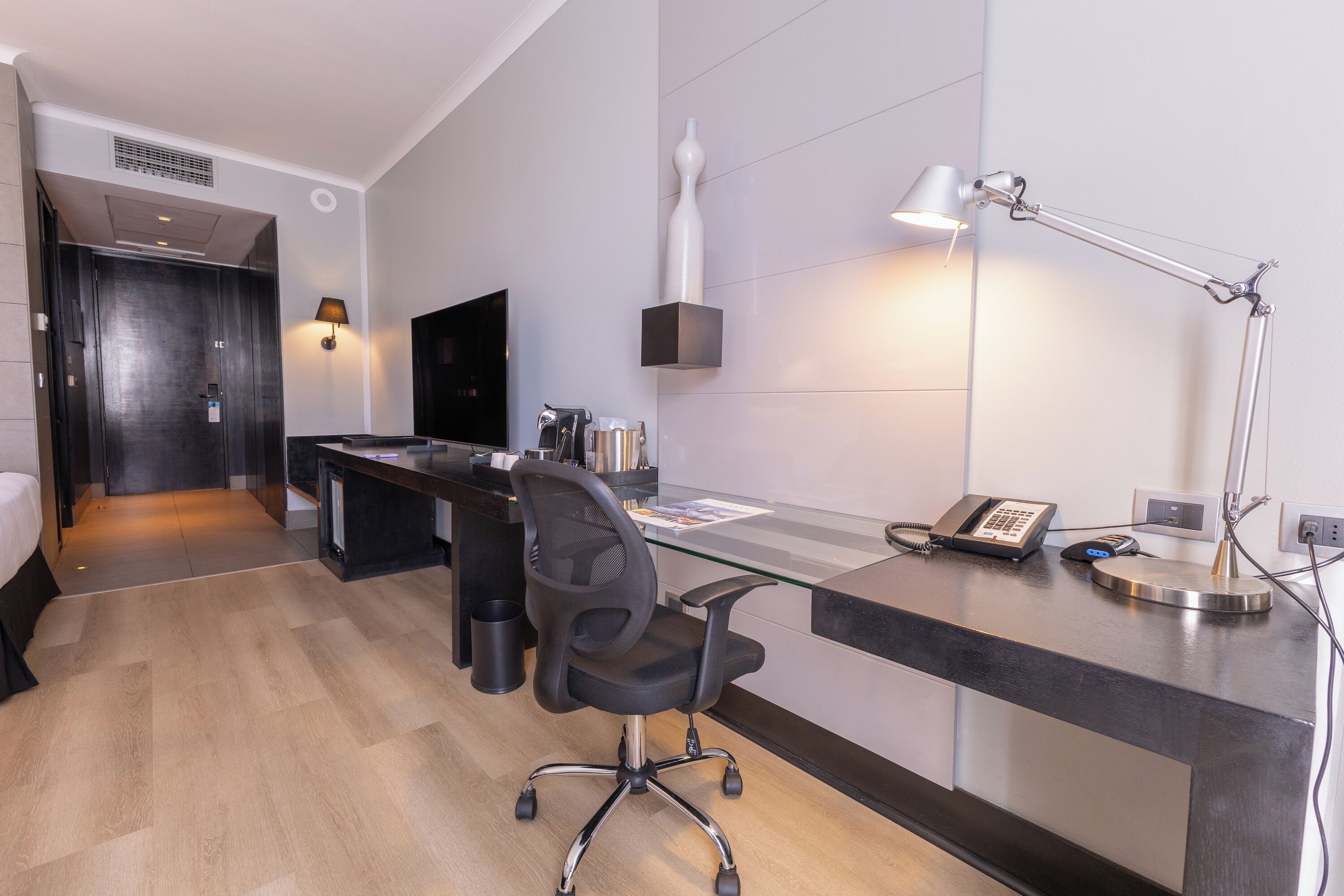 Una habitación de hotel con escritorio, silla, cama y televisor.