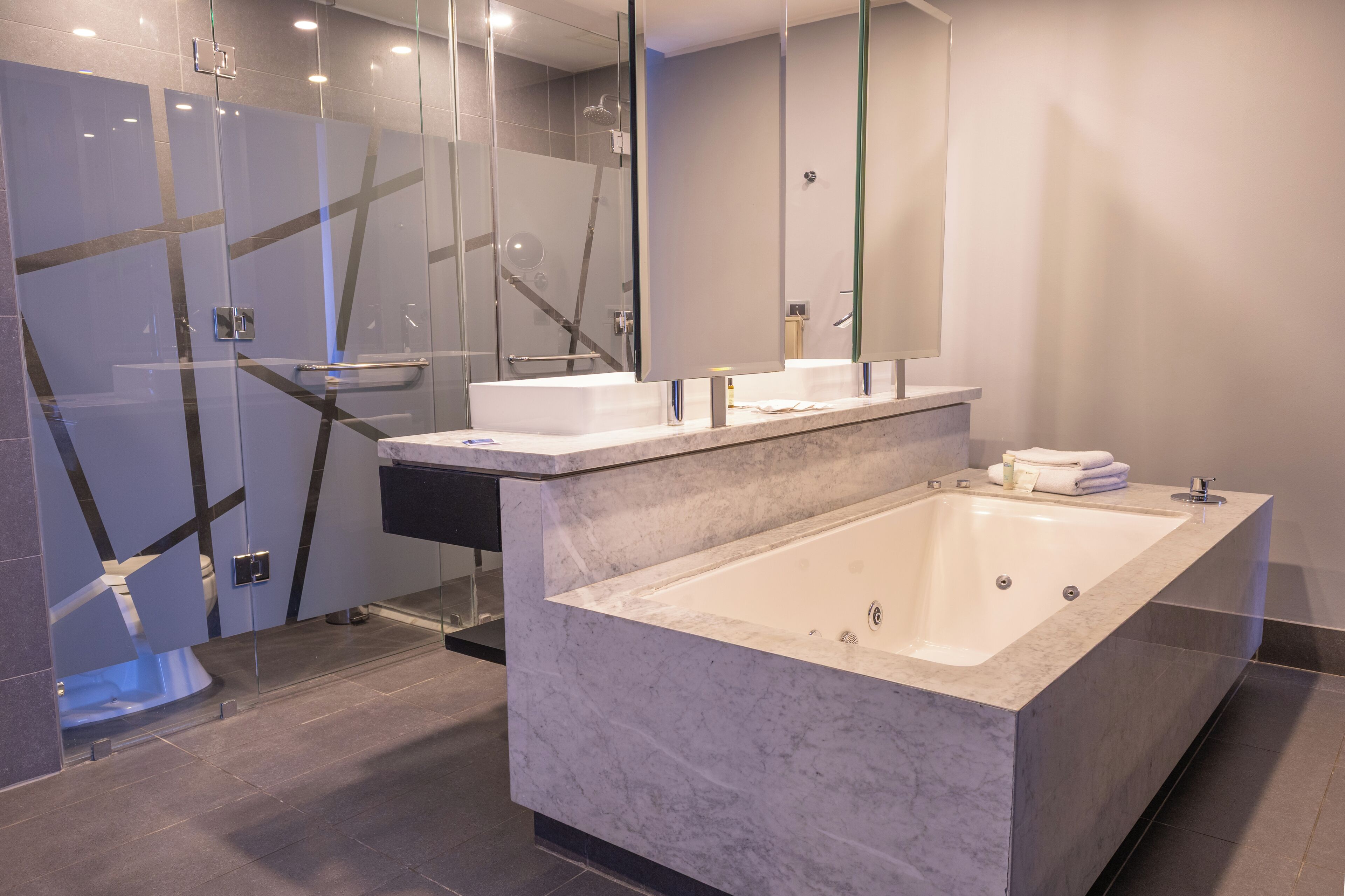 A modern bathroom with a large bathtub, a glass shower enclosure, and a vanity with a mirror.