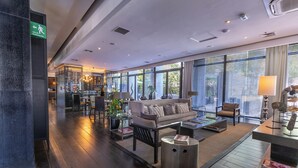 Un hall espacioso con sofá, sillones, una mesa baja y un comedor con sillas y una mesa.