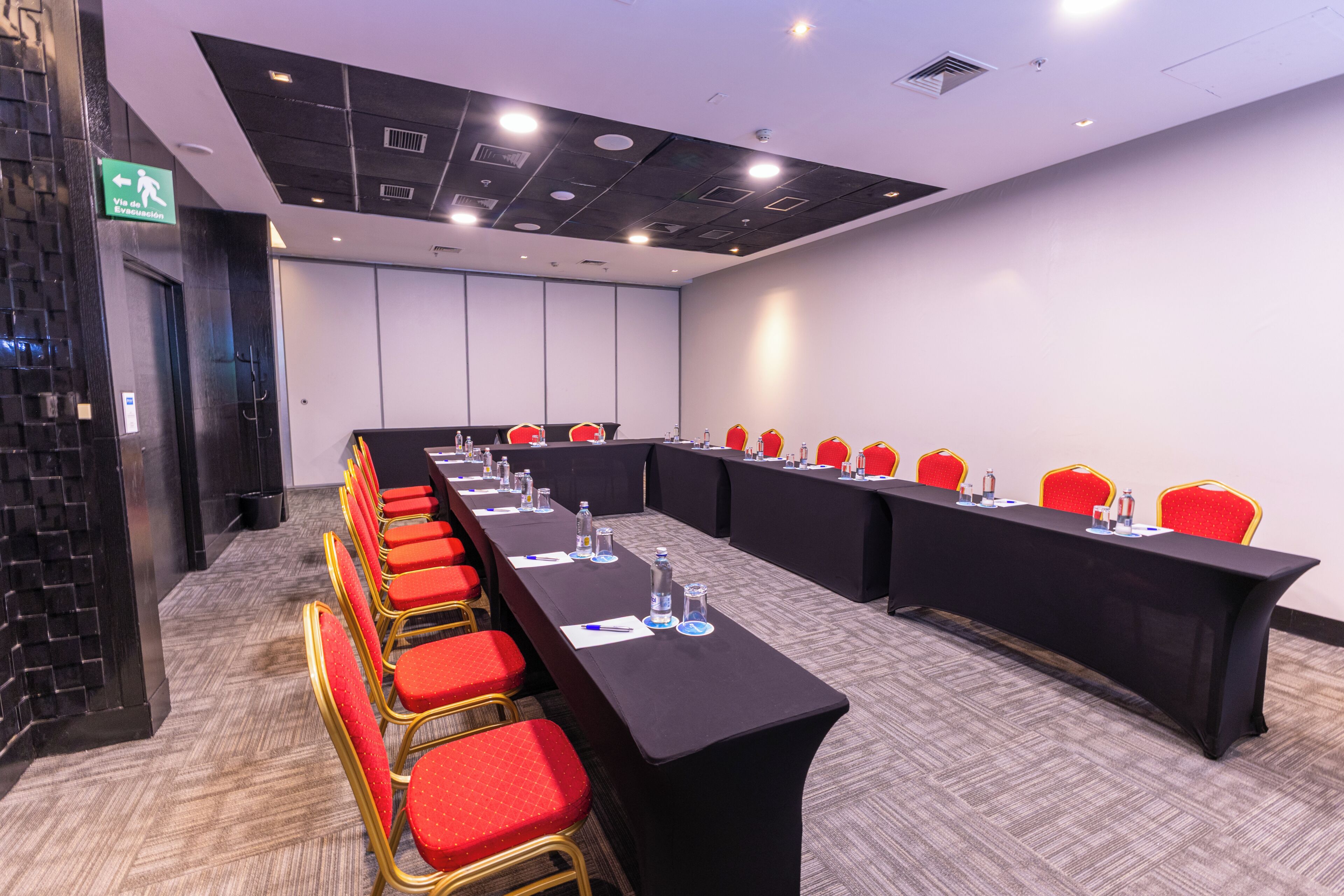 A conference room with a long table, red chairs, and a black tablecloth.