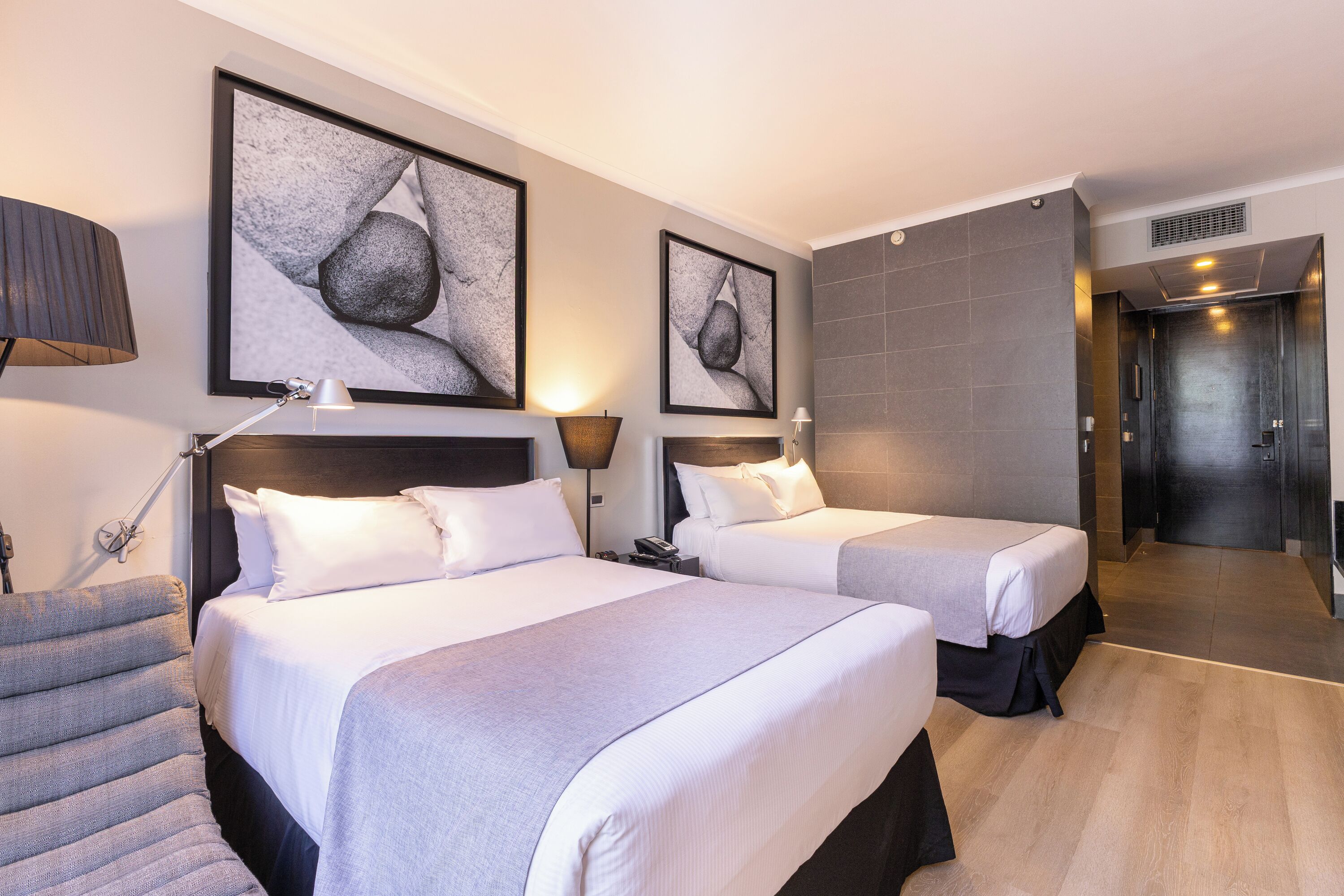 A hotel room with two beds, a sofa, and artwork on the walls.