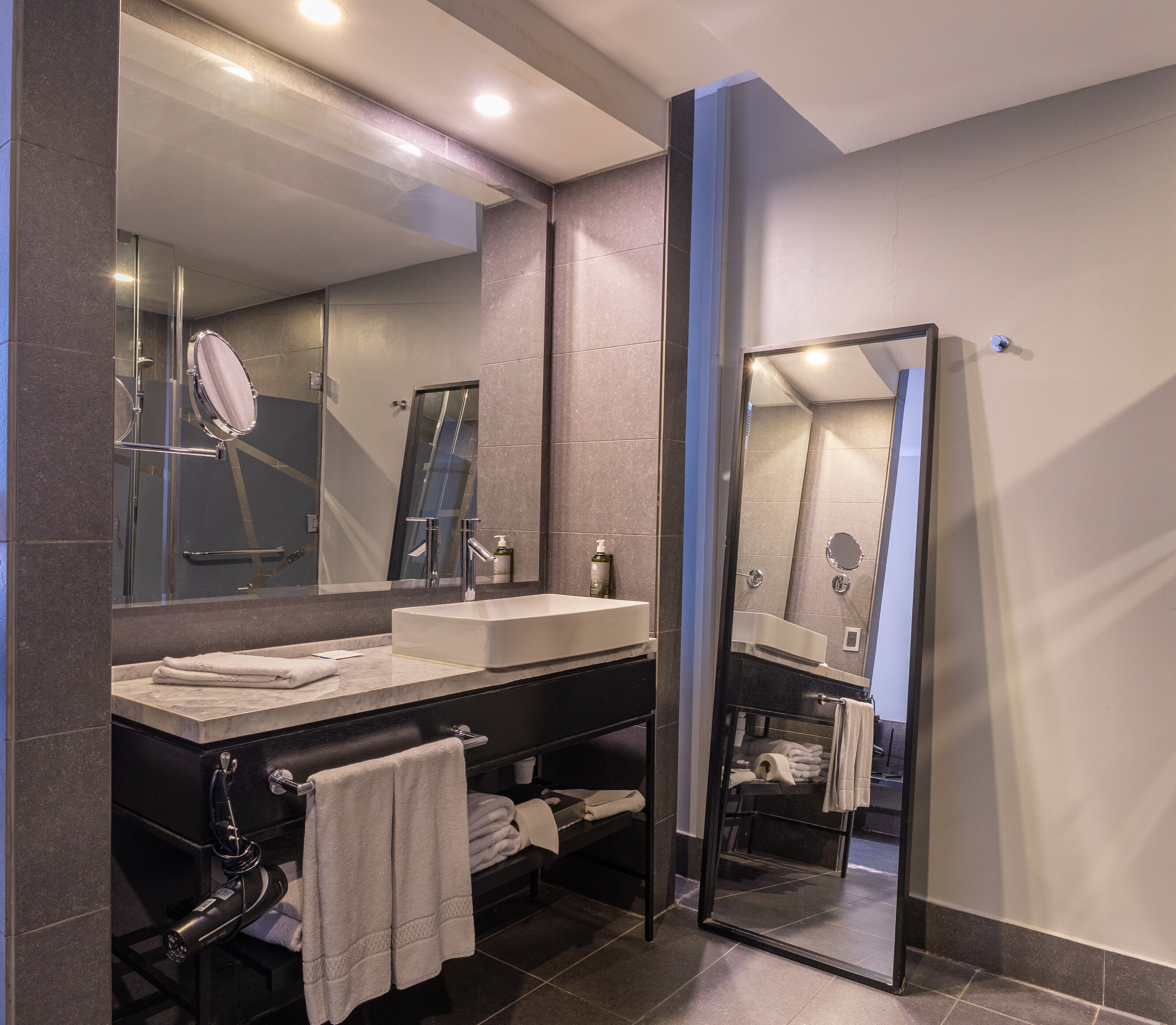A modern bathroom with a large mirror, a sink, and a towel rack.