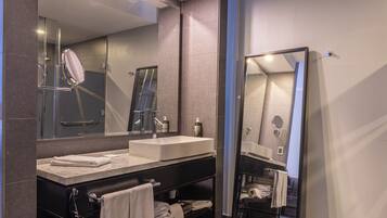 A modern bathroom with a large mirror, a sink, and a towel rack.