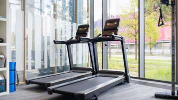 A gym with two treadmills, large windows, and a view of the outside.