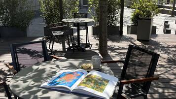 Un área exterior con mesas y sillas, un libro y un vaso de agua.