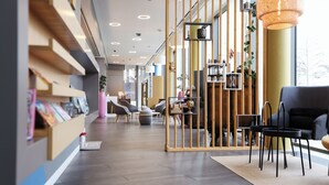 Un interior moderno con mostrador de recepción, zona de estar y una partición de madera con estantes.