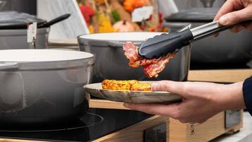 Una persona usando unas pinzas para servir comida de una olla a un plato.