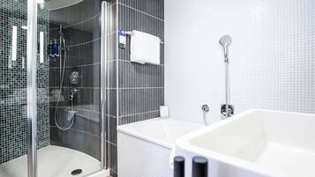 Un baño moderno con ducha envuelta en vidrio, una bañera blanca y un revestimiento de azulejos.
