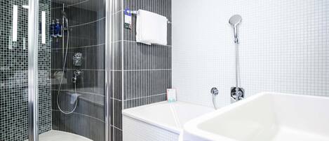 Un baño moderno con ducha envuelta en vidrio, una bañera blanca y un revestimiento de azulejos.
